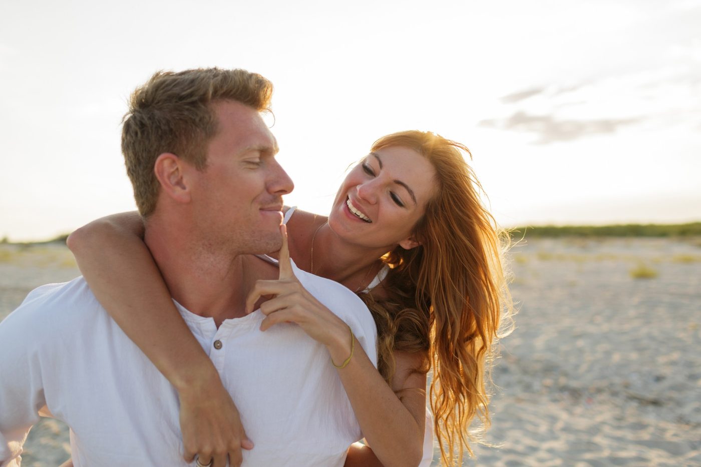 A couple laughing together on the beach at sunset